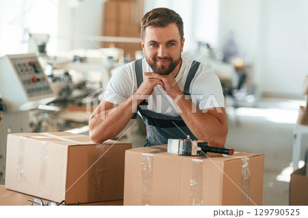 Bunch of eco boxes. Handsome man is working at the factory Bunch of eco boxes. Handsome man is working at the factory 129790525