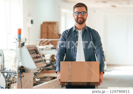In the glasses. Handsome man is working at the factory of creating eco boxes 129790651