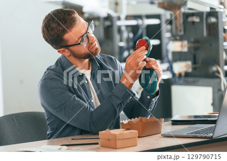 Formal clothes and glasses, by the table. Handsome man is working at the factory of creating eco boxes 129790715
