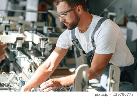Technician is working. Handsome man is at the factory of creating eco boxes Technician is working. Handsome man is at the factory of creating eco boxes 129790778