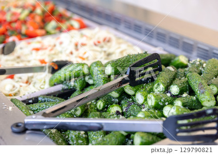 A close-up of fresh pickles with dill and garlic on a buffet counter at a market. A close-up of fresh pickles with dill and garlic on a buffet counter at a market. 129790821