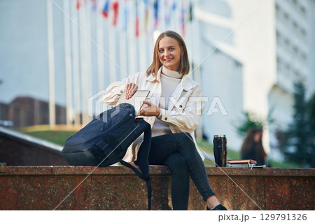 Cheerful, smiling. Young female student in casual clothes is outdoors 129791326