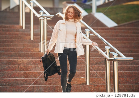 Cheerful, smiling. Young female student in casual clothes is outdoors 129791338