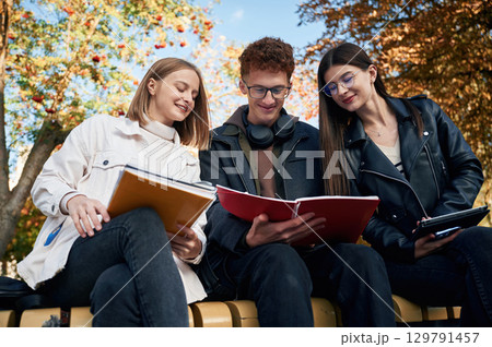 Three young students are outside the university outdoors Three young students are outside the university outdoors 129791457