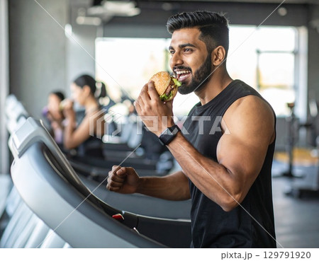 ハンバーガーを食べながら走るトレーニー　トレーニングジム　ジャンクアップジム 129791920
