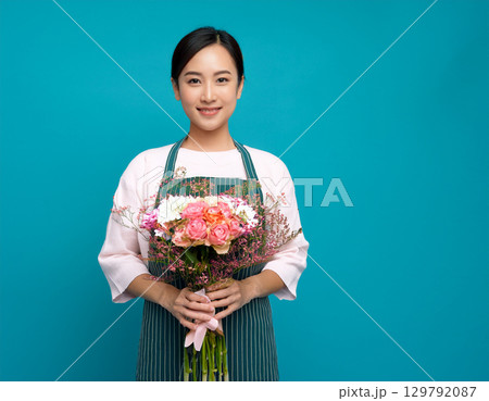 エプロンを着用し花を持っている女性 エプロンを着用し花を持っている女性 129792087
