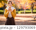 秋の公園でスイーツを持つ女性／紅葉と笑顔のイメージ 129793069