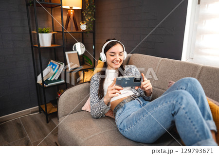 Relaxed young woman using mobile phone Relaxed young woman using mobile phone 129793671