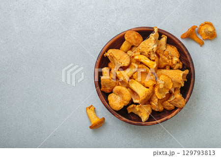Fresh chanterelle mushrooms in a a rustic bowl on gray background table top view, space for text Fresh chanterelle mushrooms in a a rustic bowl on gray background table top view, space for text 129793813
