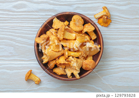 Fresh chanterelle mushrooms in a a rustic bowl on white wooden table top view Fresh chanterelle mushrooms in a a rustic bowl on white wooden table top view 129793828