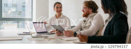 A team meeting occurs in a modern office with devices that enhance collaboration and productivity A team meeting occurs in a modern office with devices that enhance collaboration and productivity 129794157