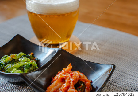 ビールとキムチや青菜のおつまみを並べた家庭的な晩酌の食卓 ビールとキムチや青菜のおつまみを並べた家庭的な晩酌の食卓 129794625