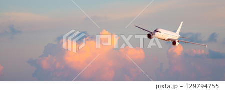 Jet plane flying high above dramatic cloudscape during golden hour Jet plane flying high above dramatic cloudscape during golden hour 129794755