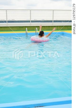 浮き輪でプールを楽しむ子どもの後ろ姿 浮き輪でプールを楽しむ子どもの後ろ姿 129795179