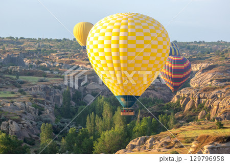 Colorful hot air balloons flying over stunning landscapes in Turkey during sunrise 129796958