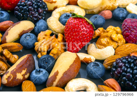 Healthy assortment of nuts and berries on a dark surface during daylight 129796966