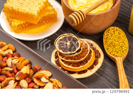 Natural honey and dried fruit arrangement with nuts and propolis on dark wood background 129796991