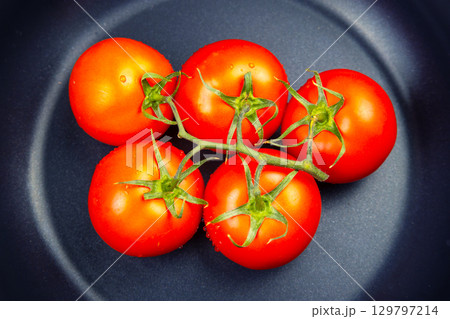 Fresh ripe tomatoes arranged on a dark plate ready for preparation or serving 129797214