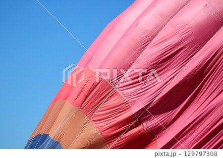Colorful hot air balloon preparing for flight against clear blue sky 129797308