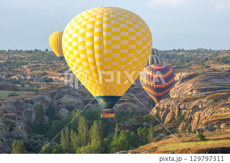 Hot air balloons drift over Cappadocia landscape in Turkey during sunset 129797311