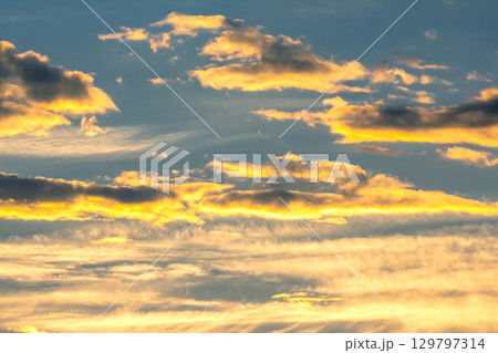 Majestic sunset sky filled with colorful clouds over tranquil horizon at dusk 129797314