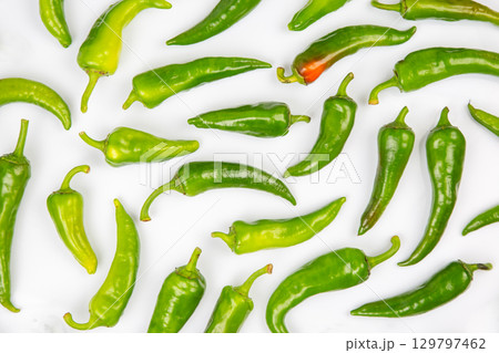 Colorful array of assorted green chili peppers on a white background for culinary uses 129797462