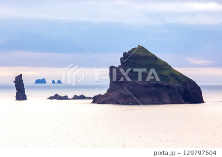 Unique coastal rock formations surrounded by calm waters near the shores of Iceland Unique coastal rock formations surrounded by calm waters near the shores of Iceland 129797604