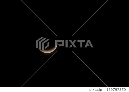 Solitary Crescent Moon Against a Pitch-Black Night Sky 129797870