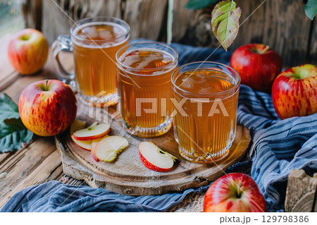 Apple Cider in Glasses on Rustic Table with Fresh Apples. 129798386