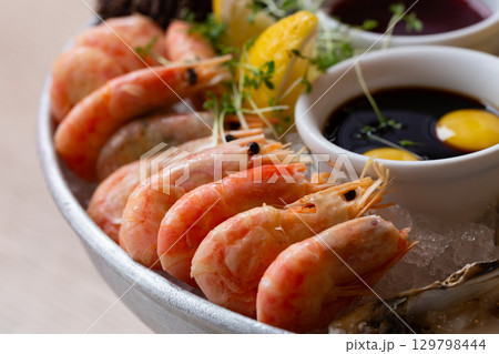 Cooked shrimps on plate with lemon, salt, sauce. Seafood appetizer. Shrimps close-up. Prepared large prawns 129798444