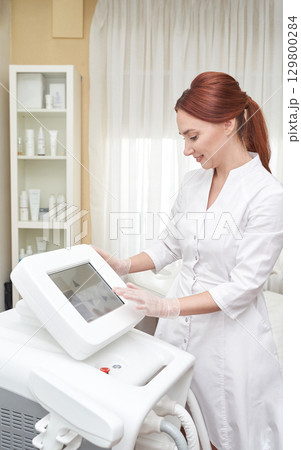 Young caucasian female technician operating skincare equipment in clinic setting 129800284
