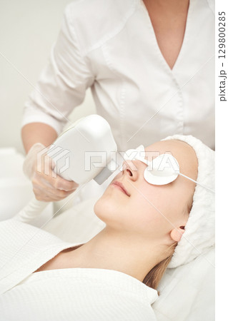Female caucasian adult receiving facial laser treatment in spa clinic 129800285