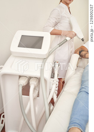 Female technician performing coolsculpting procedure on adult patient using 129800287