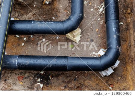 New modern insulated urban pipeline installation construction site  exposed underground pipes in shored trenches. Insulated steel pipes lie connection engineering infrastructure upgrade work 129800466