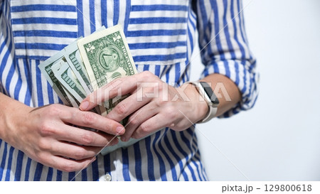 Person Holding a Stack of US Dollar Bills, Financial Security and Investment Concept 129800618