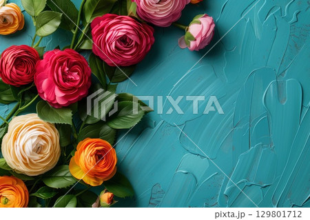 Colorful ranunculus flowers resting on a textured turquoise background 129801712