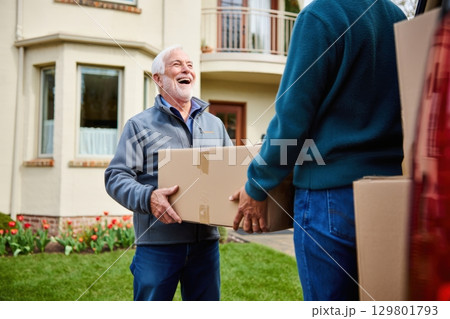 Two senior men carrying cardboard box, moving into new house 129801793