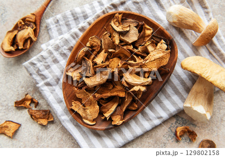 Dried mushrooms on wooden plate with fresh mushrooms and kitchen towel 129802158