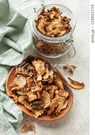 Dried mushrooms on wooden plate with fresh mushrooms and jar Dried mushrooms on wooden plate with fresh mushrooms and jar 129802159