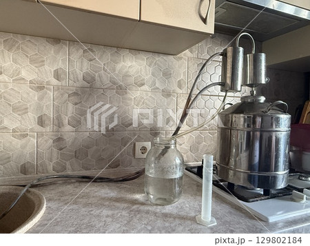 Distilling alcohol using moonshine still in kitchen 129802184