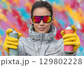 Street artist holding spray paint cans in front of colorful graffiti wall 129802228