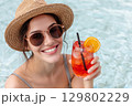 Tourist enjoying refreshing cocktail in swimming pool during summer vacation 129802229