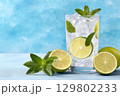 Refreshing mojito cocktail with lime, mint and ice cubes on blue background 129802233