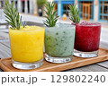 Colorful frozen cocktails garnished with rosemary sprigs on wooden tray 129802240