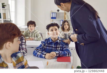 Woman teacher in junior high school helping a boy during a lesson in the classroom. Woman teacher in junior high school helping a boy during a lesson in the classroom. 129802448
