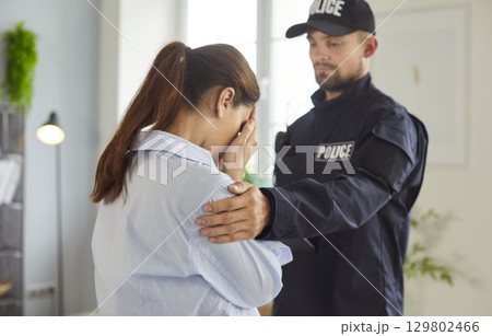 Male police officer in uniform consoling distressed woman Male police officer in uniform consoling distressed woman 129802466