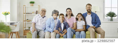 Banner background with a group portrait of a happy family sitting on the sofa at home 129802507