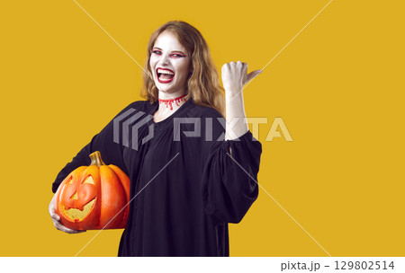 Happy woman in spooky costume isolated on yellow background inviting you to Halloween party 129802514