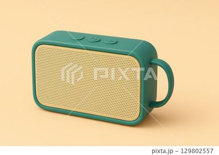 Portable wireless speaker with green casing and beige front grille, featuring control buttons and handle, set against soft peach background 129802557