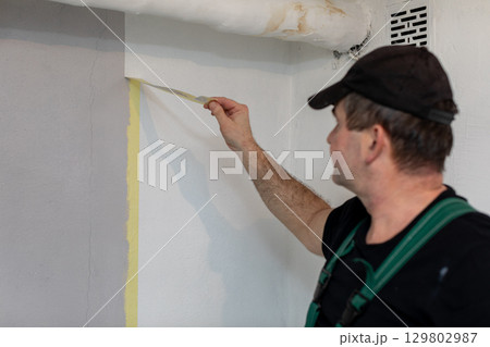 An Expert Painter is Thoroughly Preparing Walls for a Brand New Fresh Coat of Paint 129802987